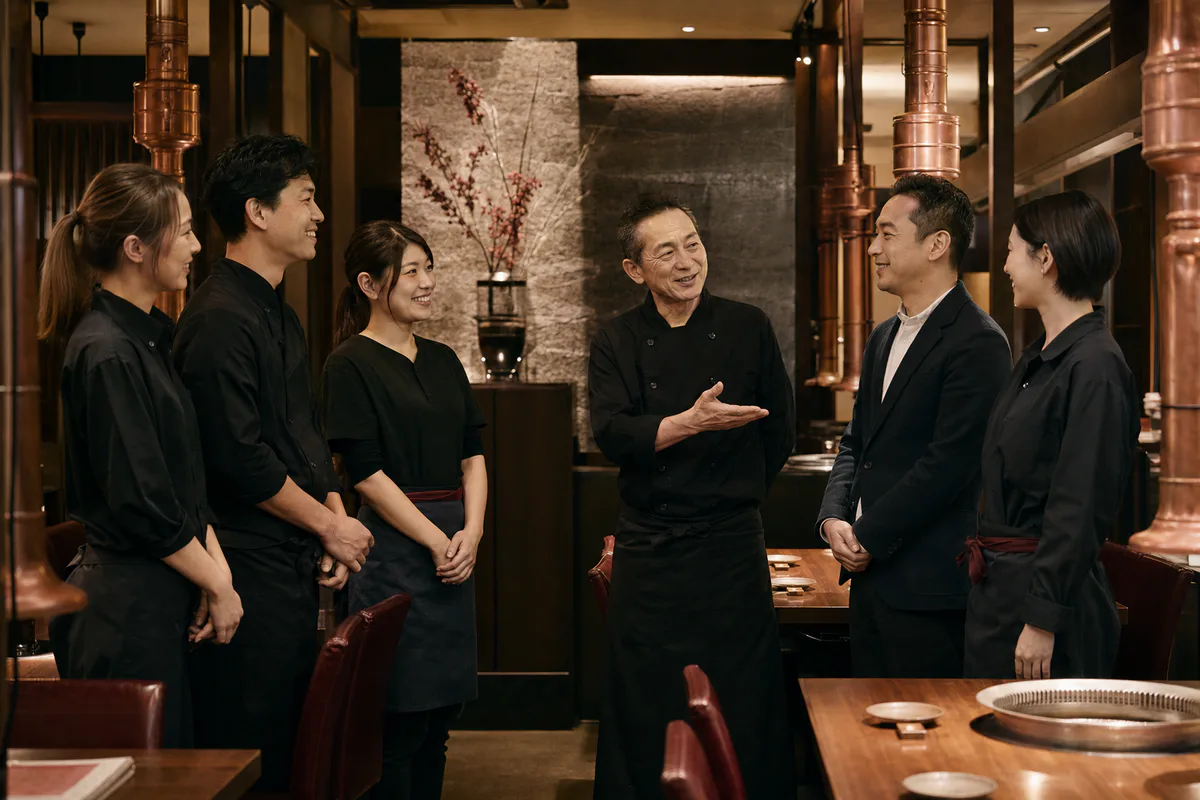 営業前に焼肉店の引き継ぎを行う現経営者と次の運営者とスタッフ
